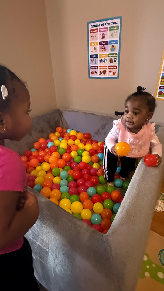 Young child enjoying supervised play in a colorful ball pit at Advanced Childcare Services LLC